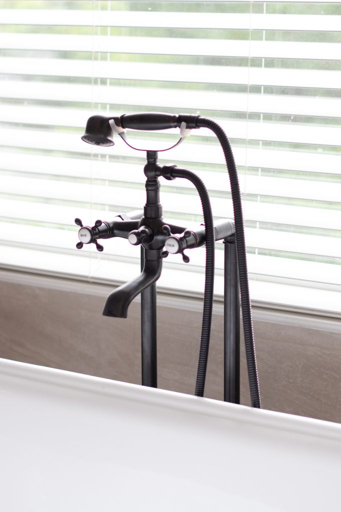Black ceiling-mount rain shower head above a corner bench and triple niche in marble-look tile.