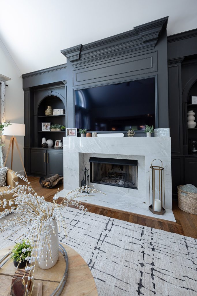 White kitchen with a gas-cooktop island, veined quartz counters, iron lantern pendants, and a wood cupola ceiling.