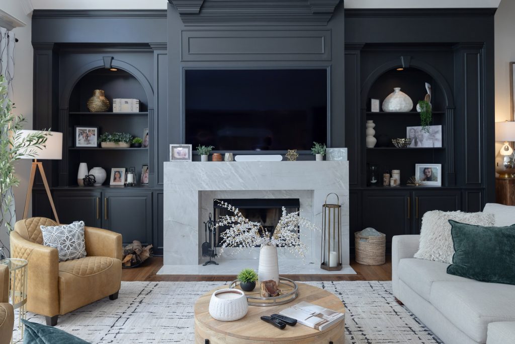 Living room with charcoal built-ins, arched niches, a veined marble fireplace surround, and mounted TV.