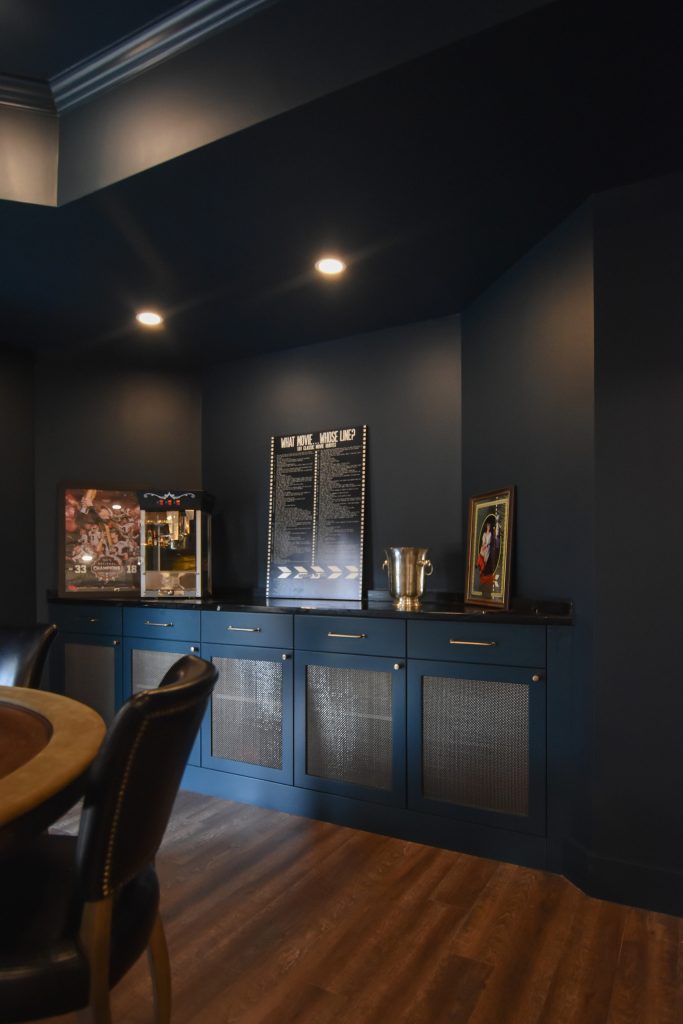 Custom blue built-in cabinetry with metal mesh door panels and brass pulls beneath a black stone countertop