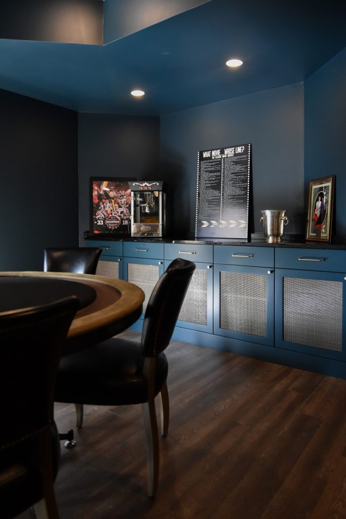 Custom blue built-in cabinetry with mesh door inserts beside a poker table in a finished basement