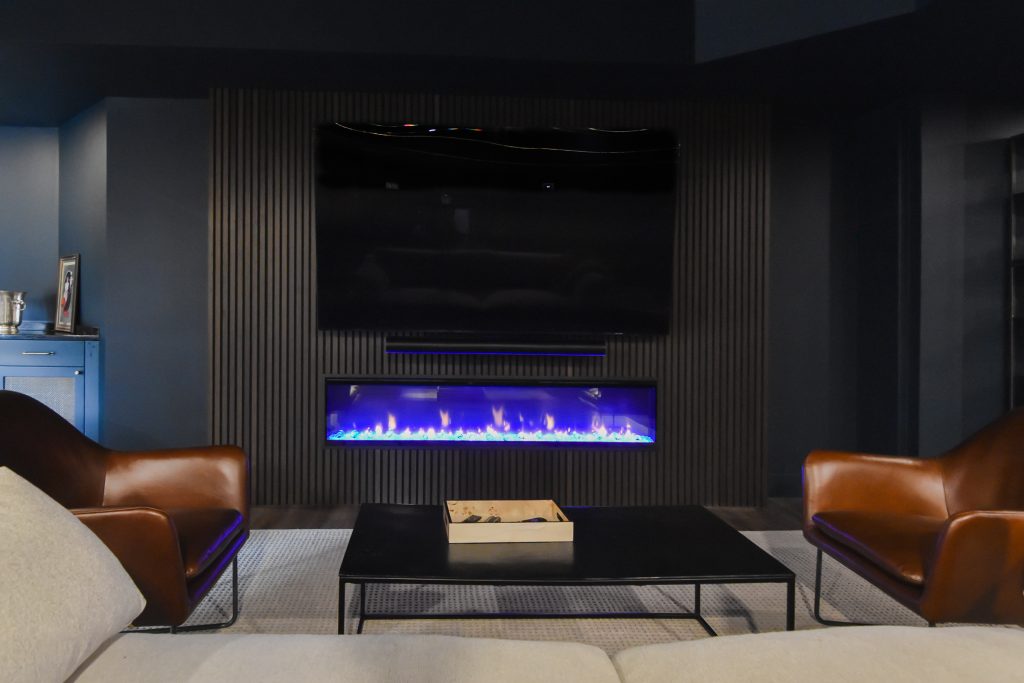 Mounted TV above a linear electric fireplace set into a slatted wood media wall in Cumming, GA