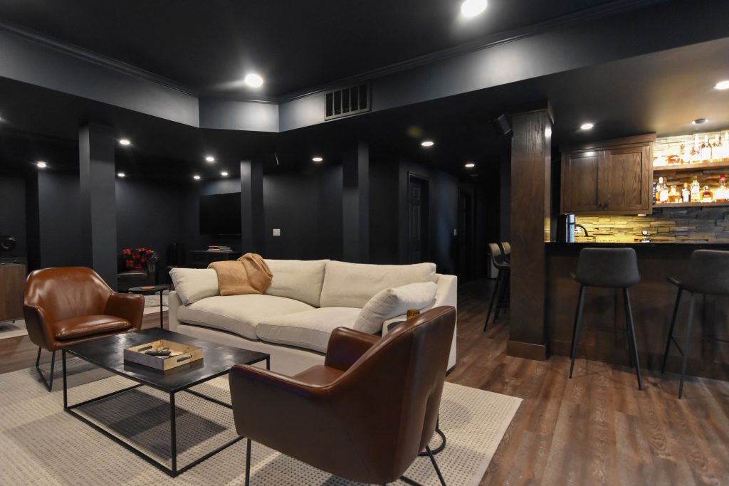 Basement lounge seating looking toward the custom wet bar and stacked stone backsplash