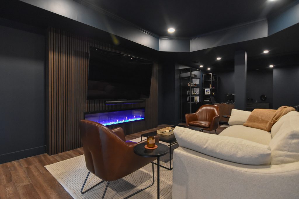 Finished basement lounge with fireplace media wall, sectional seating, and built-in shelving