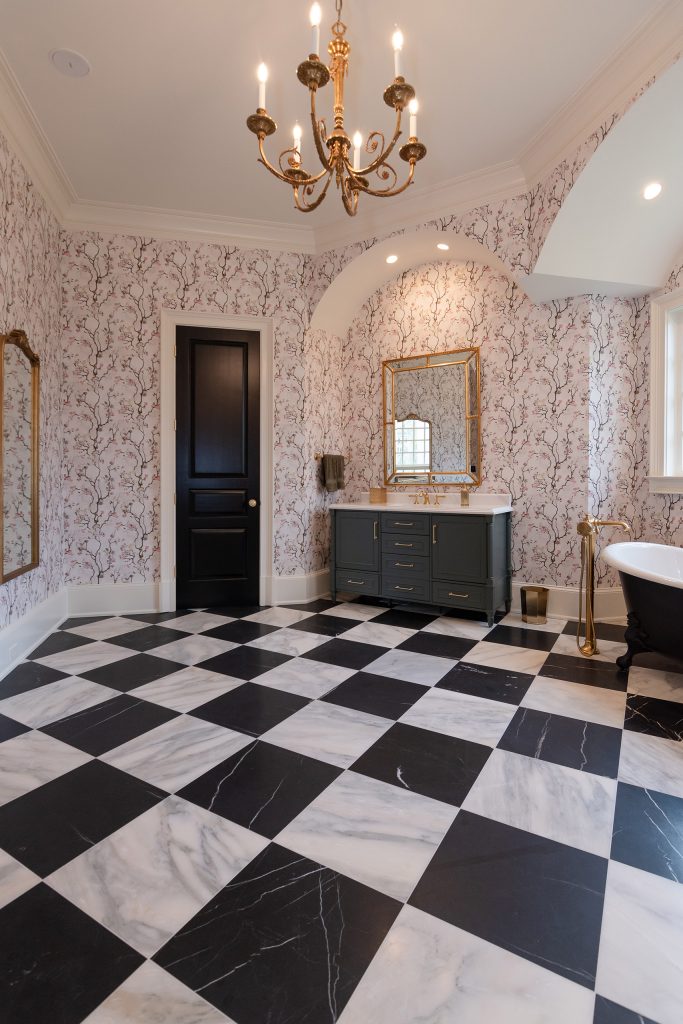 Vaulted bath with black paneled door, charcoal vanity, and black clawfoot tub over dramatic checkerboard marble.