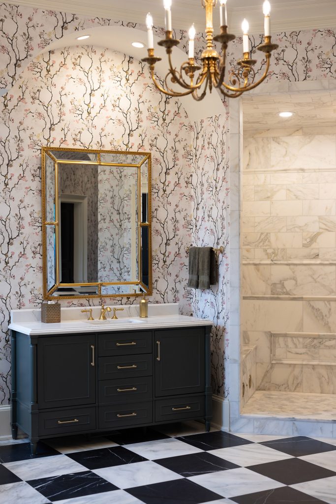 Black cast-iron slipper clawfoot tub with brushed-gold filler below a window, on black-and-white checkerboard marble.