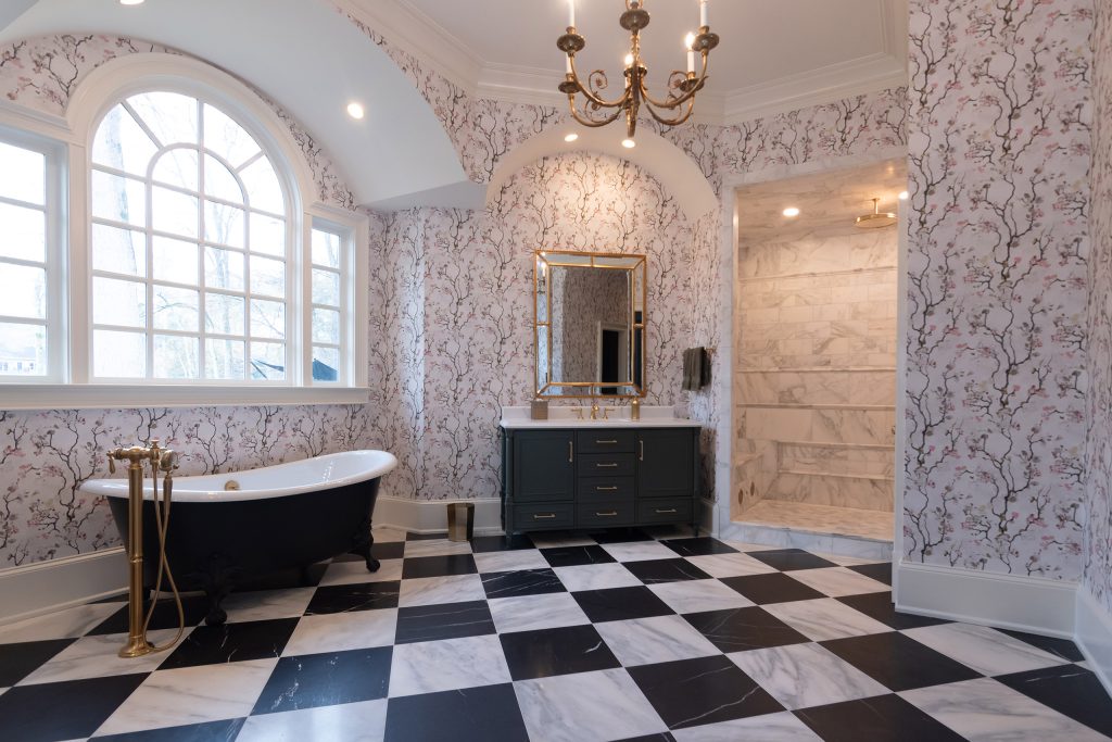 Symmetrical vaulted bath with arched window, black clawfoot tub, charcoal vanity, and marble shower alcove.