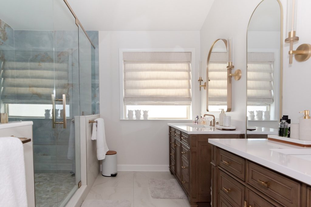Master bath with dark walnut double vanities, white quartz tops, gold fixtures, and a blue stone shower feature wall.