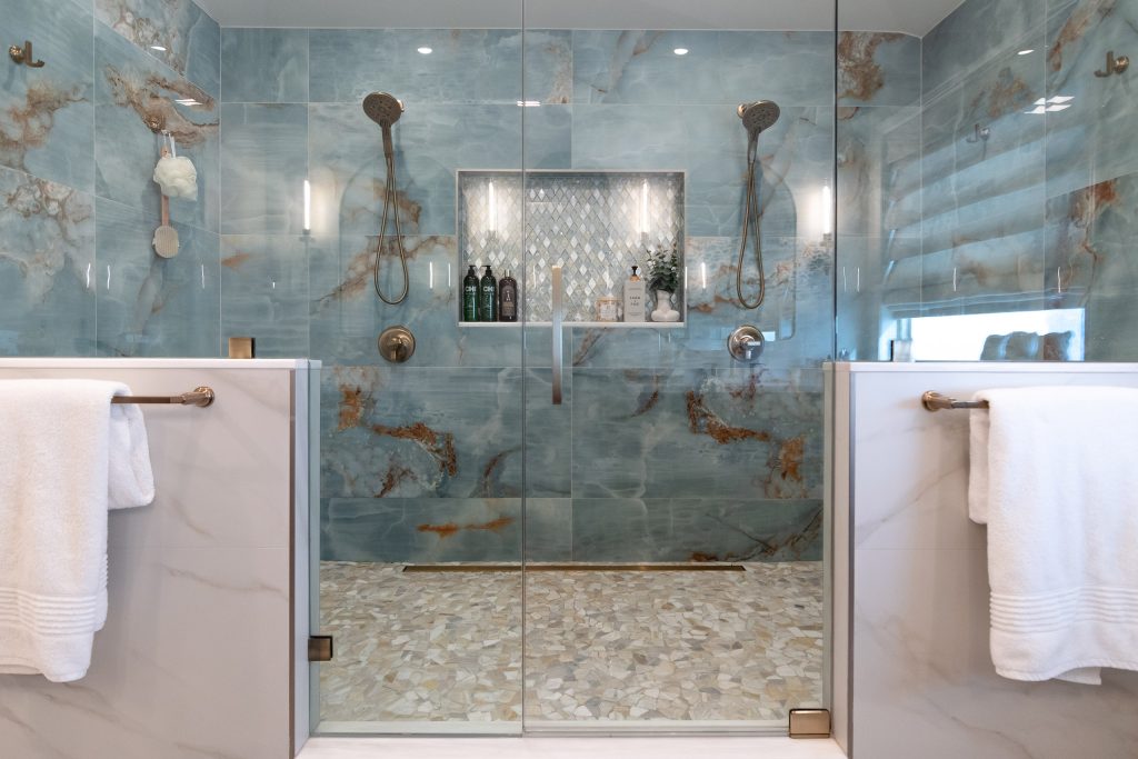 Dual-head blue onyx shower with a centered diamond mosaic niche, flanked by marble-clad half-walls with white towels.
