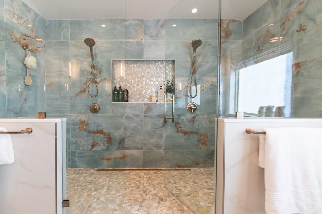 Straight-on blue onyx shower with dual brushed-nickel shower heads, a centered diamond mosaic niche, and a pebble floor.