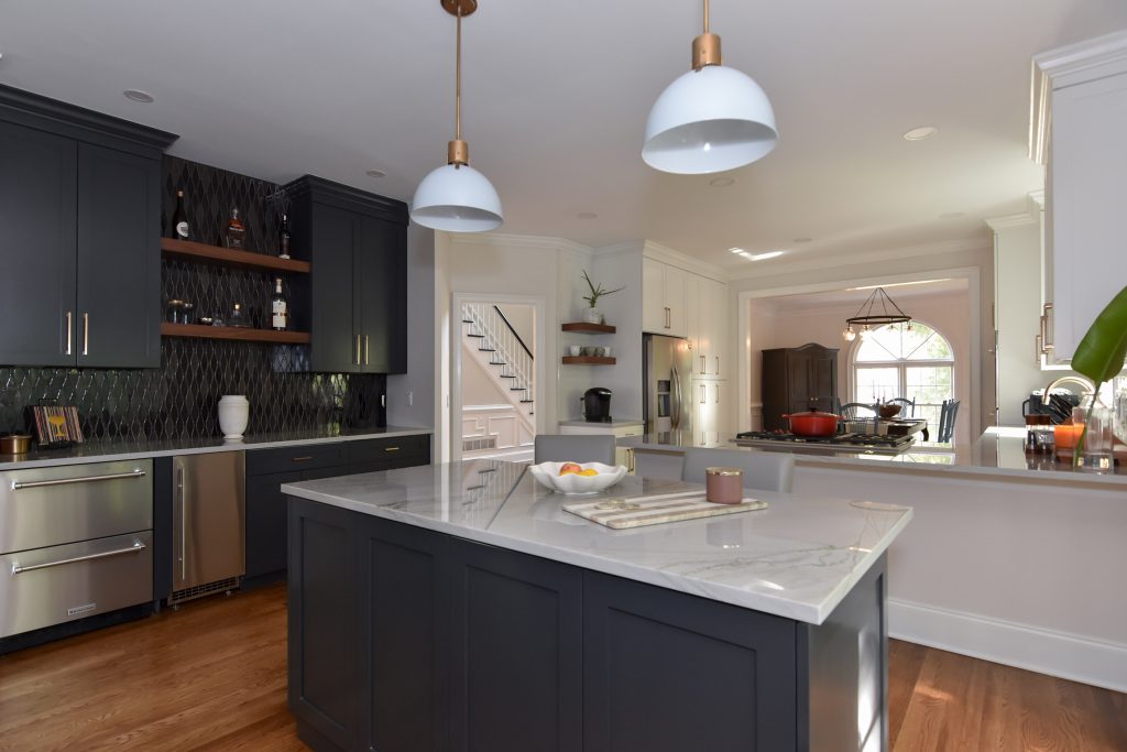 Navy island with veined marble top, navy bar at left, and a view to a breakfast area with an arched window in Alpharetta.