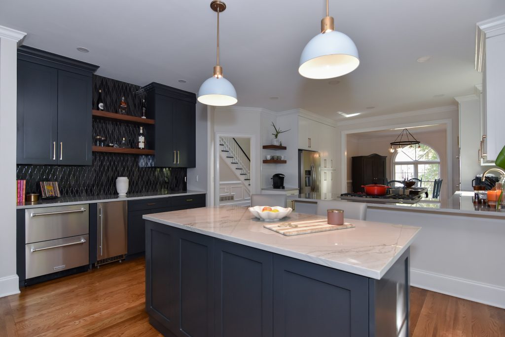 Navy island with veined marble top under gray pendants, with the navy bar wall at left in an open Alpharetta kitchen.