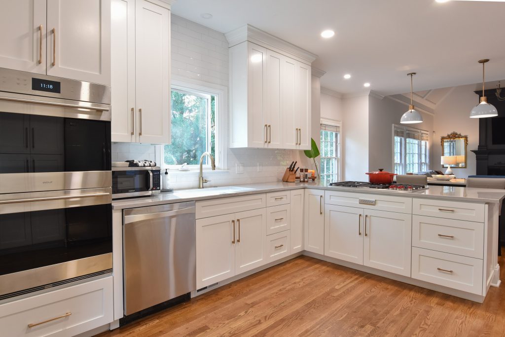 White L-shaped Alpharetta kitchen with stainless double wall ovens, an undermount sink, subway tile, and gray quartz counters.