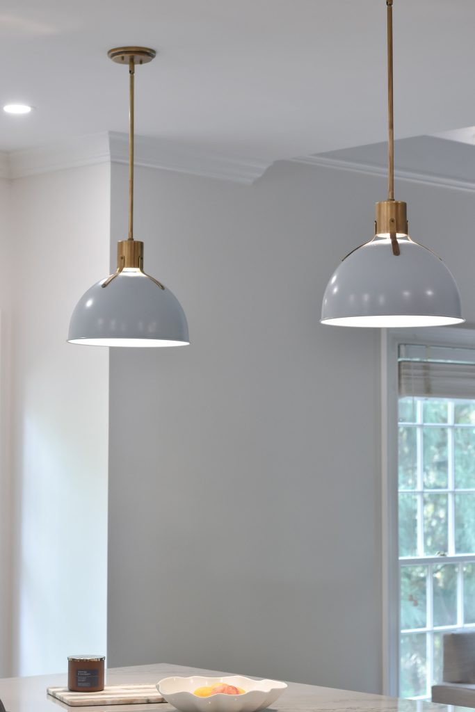 Two gray dome pendants with brushed-brass fittings hanging against a soft gray wall near a window in Alpharetta.