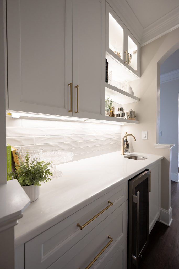 Two tall white shaker cabinets with brushed-gold bar pulls flanking a stainless French-door refrigerator.