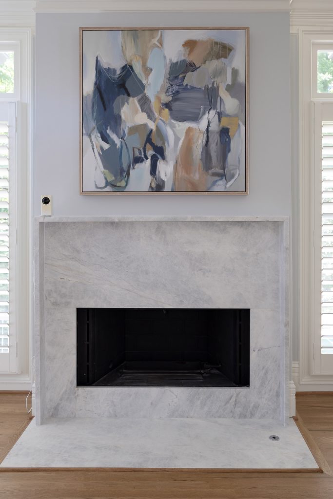 Grey veined quartzite fireplace with a blue-toned abstract painting centered above the firebox.