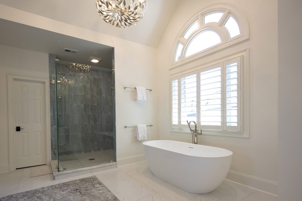 Bedroom fireplace with a veined quartzite slab surround, an abstract painting above, and plantation shutters.