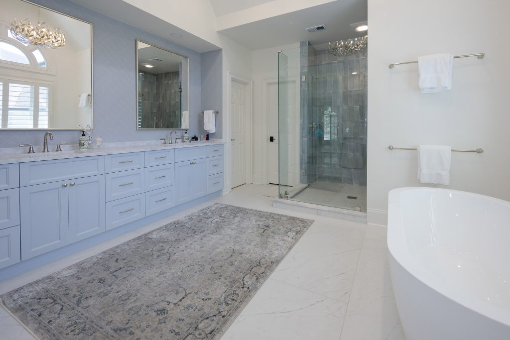 Master bathroom with a freestanding tub, arched window, white built-in cabinet, and a makeup nook.