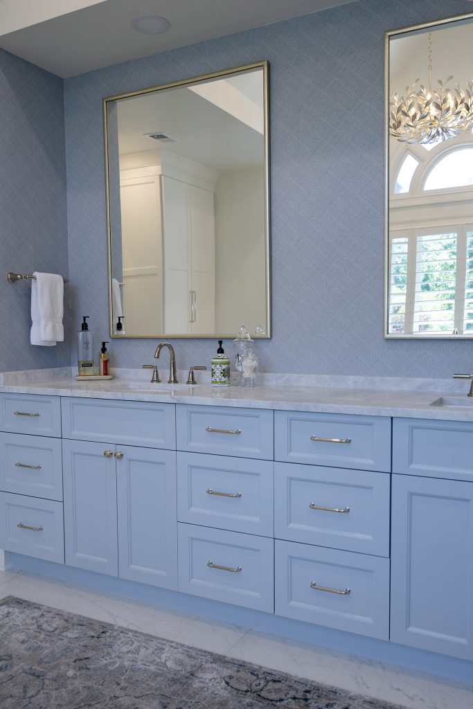 Spacious master bath with a light-blue vanity, marble-tile floor, glass shower, and a freestanding soaking tub.
