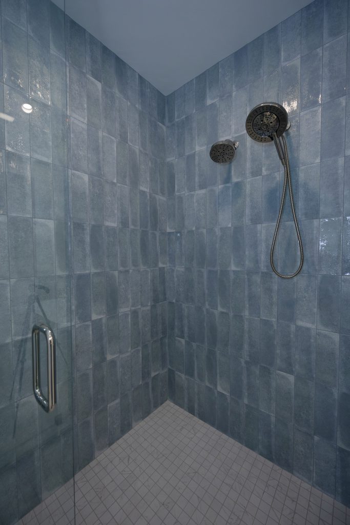 Powder-blue double vanity with a marble top, twin gold-framed mirrors, and blue grasscloth walls.
