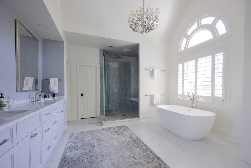 Tall white linen cabinet beside a marble-topped makeup vanity with a skirted stool and blue grasscloth walls.