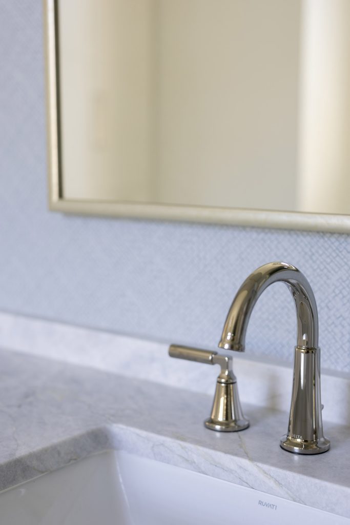 Polished-nickel widespread faucet on a veined marble counter with a white undermount sink.