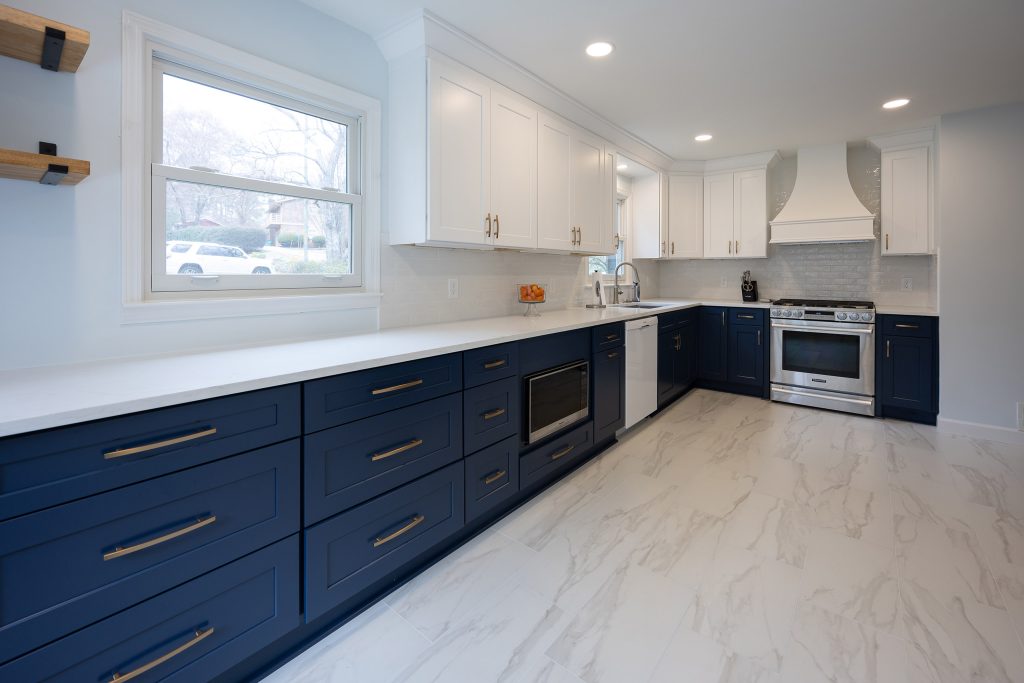 Two-tone kitchen with navy lower cabinets, white uppers, brushed-gold hardware, and white quartz counters.
