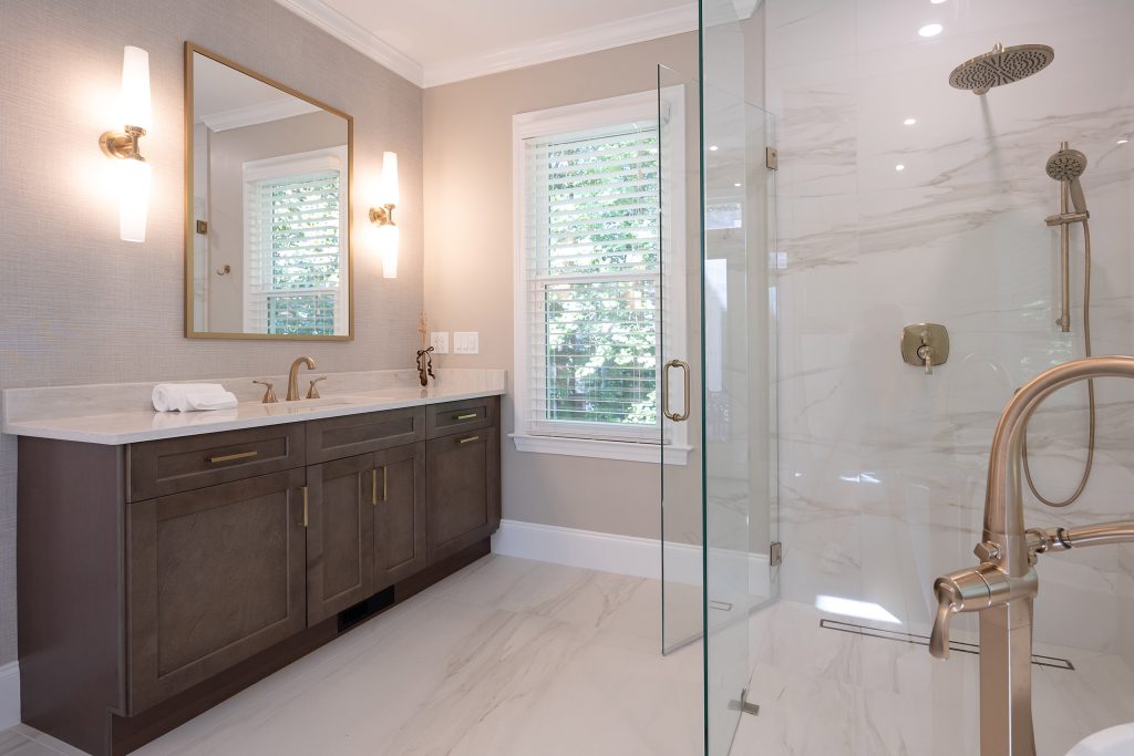 Dark shaker vanity with cream quartz top facing a marble-look glass shower with a satin tub filler.