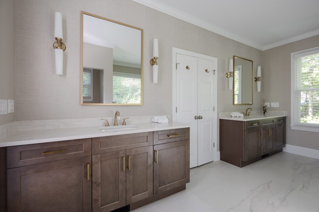 Double-vanity master bath with dark shaker cabinets, white quartz tops, gold-framed mirrors, and white-glass sconces.