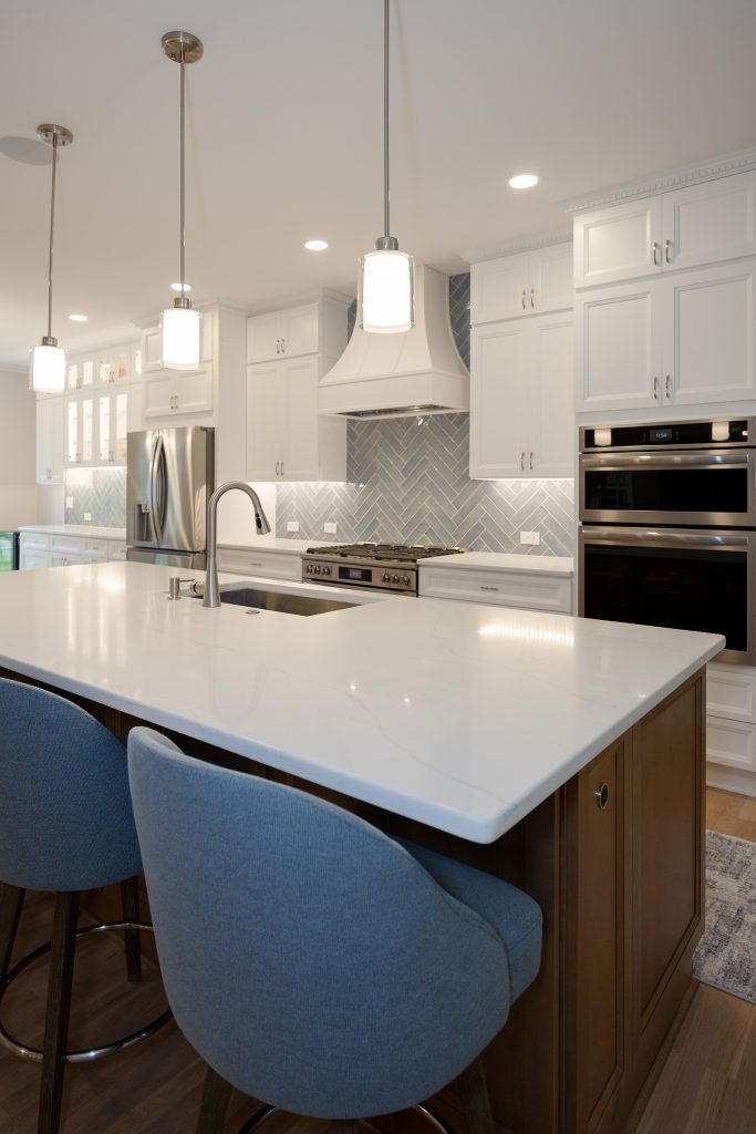 Waterfall of quartz across the island with an undermount sink, looking toward the range and custom hood.