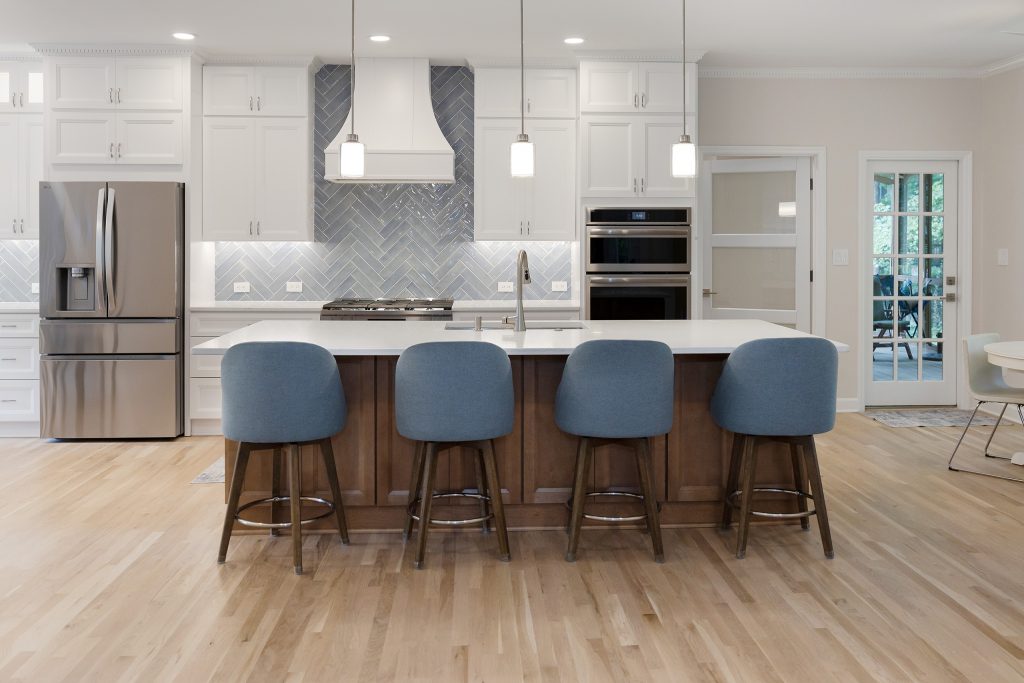 Kitchen and island from the family room, with the screened porch doors and white oak flooring running throughout.