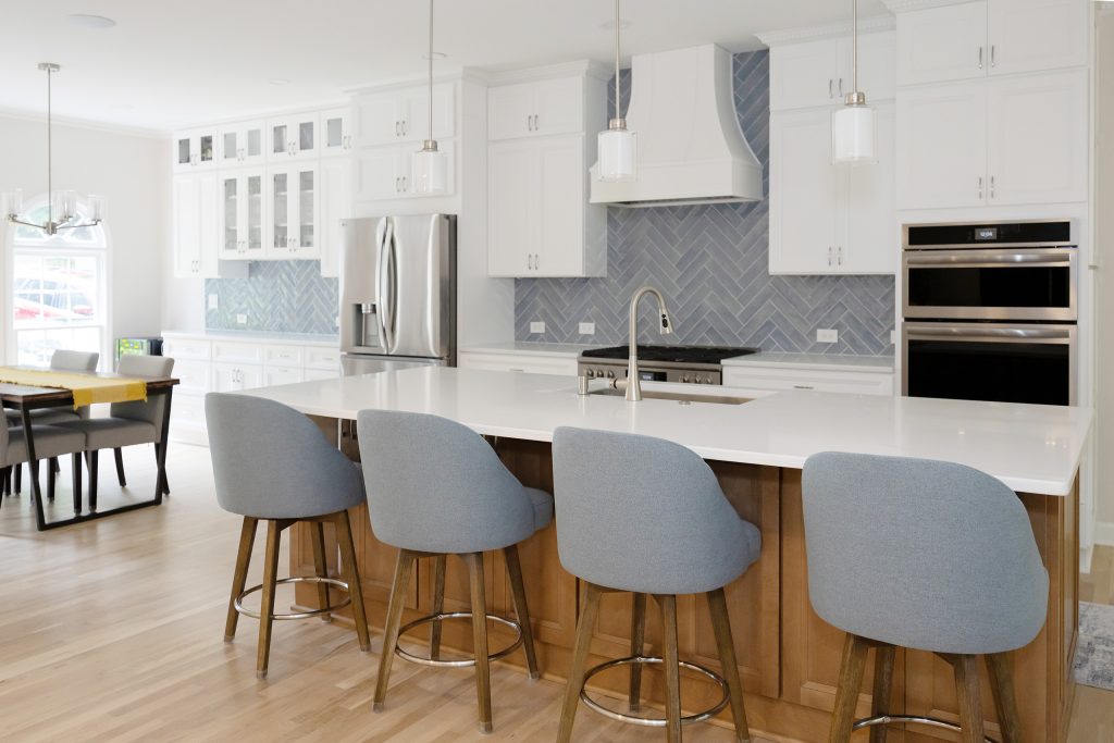 Daylit kitchen with the island sink, double wall ovens and refrigerator framing the range wall.