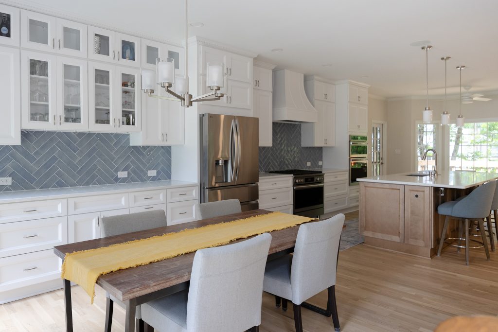 Dining table with the bar cabinetry along the left wall and the kitchen island beyond.