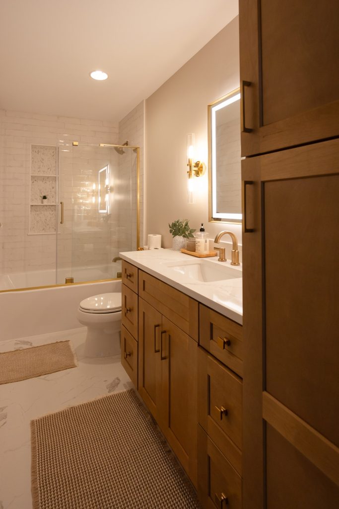 Bathroom looking toward the tub and glass enclosure, with the maple vanity and linen tower to one side.